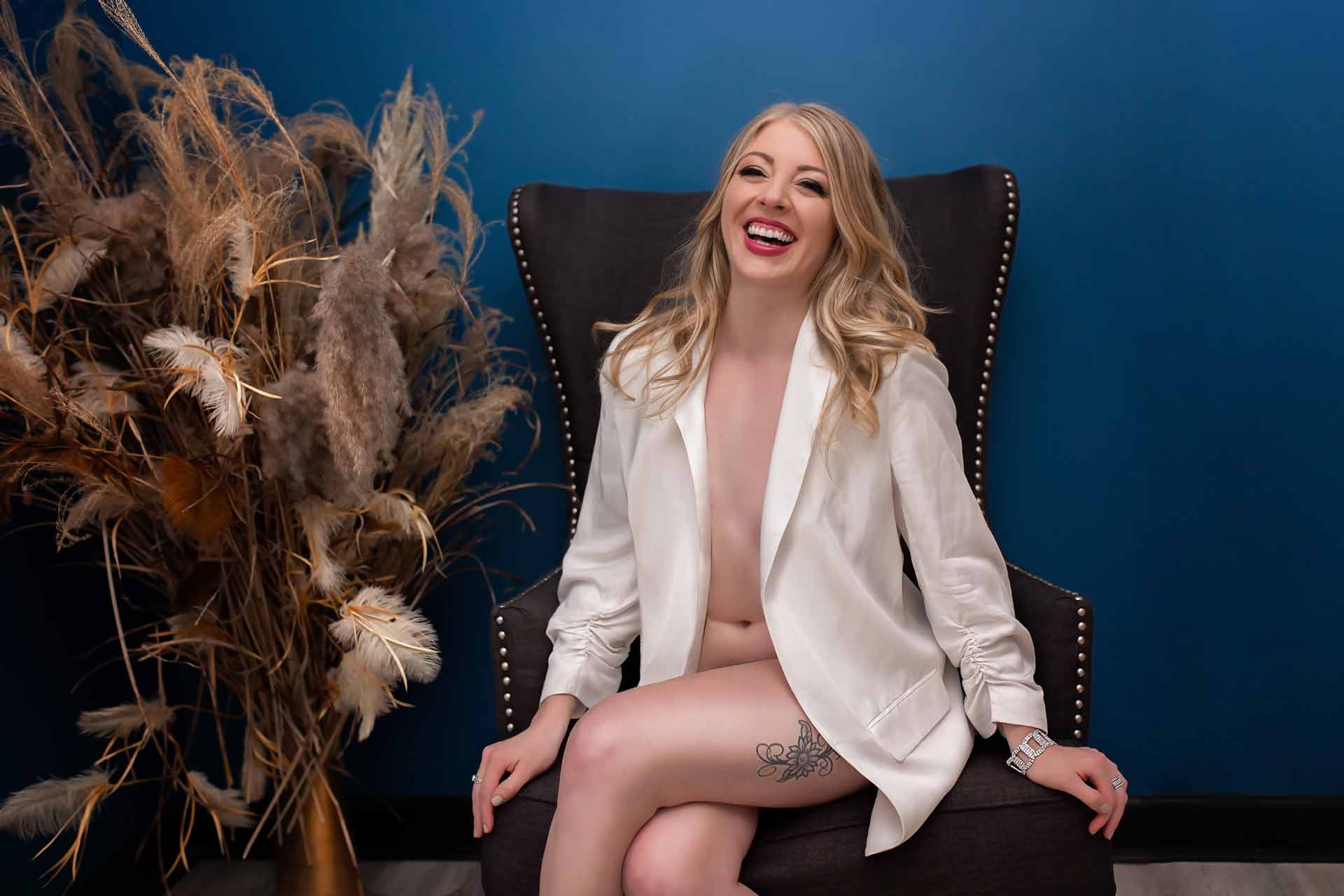 A woman sitting in a chair wearing nothing but a white blazer