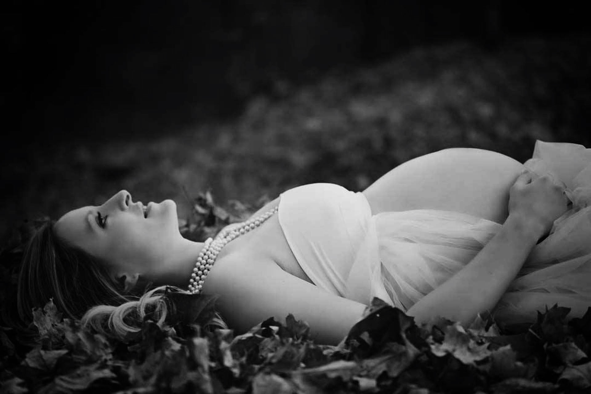 A pregnant woman laying on the ground outside